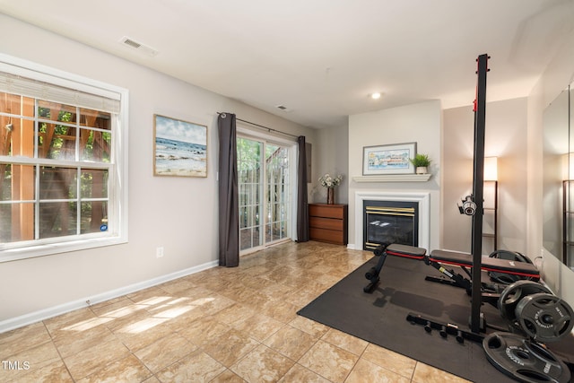 workout room with baseboards, visible vents, and a glass covered fireplace