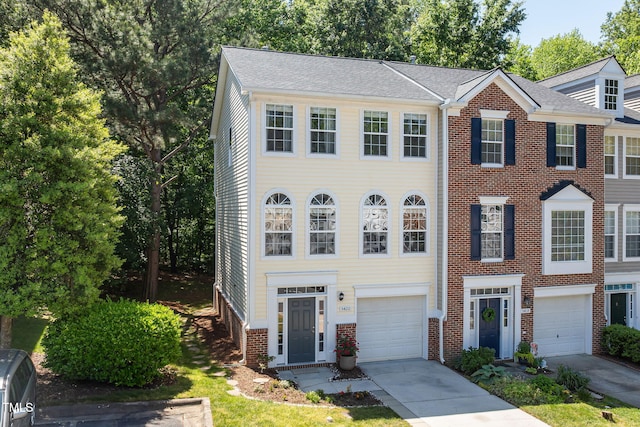 view of property featuring brick siding, driveway, and a garage