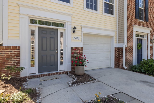 property entrance with an attached garage, driveway, and brick siding