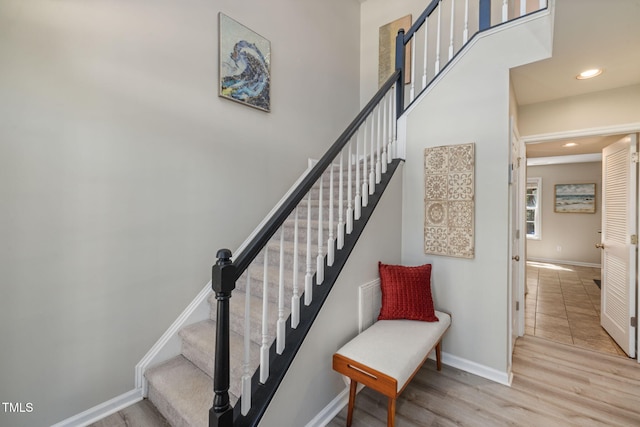 stairs with recessed lighting, baseboards, wood finished floors, and a towering ceiling