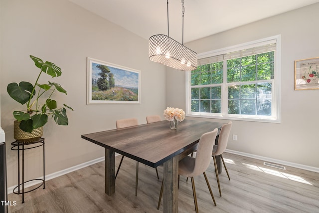 dining room featuring visible vents, light wood finished floors, baseboards, and a wealth of natural light