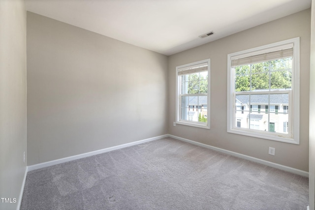 spare room featuring baseboards, visible vents, and carpet
