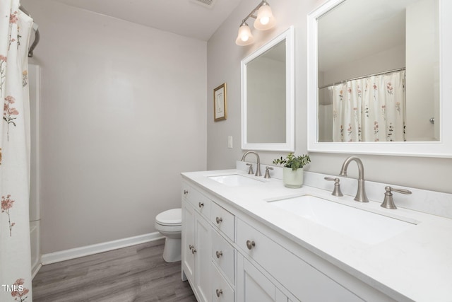 bathroom featuring baseboards, a sink, wood finished floors, and toilet