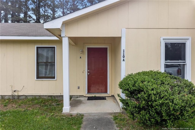 view of exterior entry featuring roof with shingles