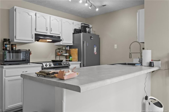 kitchen featuring a peninsula, under cabinet range hood, white cabinets, a sink, and stainless steel appliances