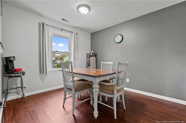 dining area featuring baseboards, wood finished floors, a textured ceiling, and visible vents