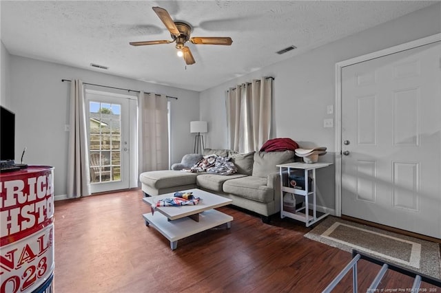 living area with a textured ceiling, ceiling fan, visible vents, and wood finished floors
