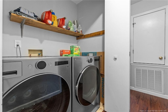 laundry area featuring washing machine and clothes dryer, laundry area, visible vents, and wood finished floors