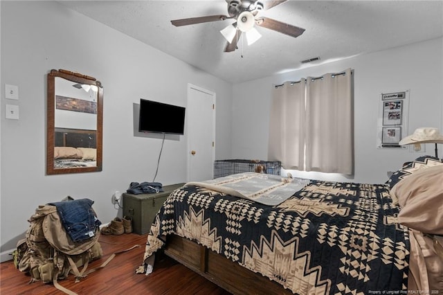 bedroom with a ceiling fan, visible vents, and wood finished floors