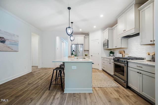 151 Monteith Dr, Chapel Hill, NC 27516 - kitchen featuring stainless steel appliances, a sink, backsplash, wood finished floors, and a breakfast bar area