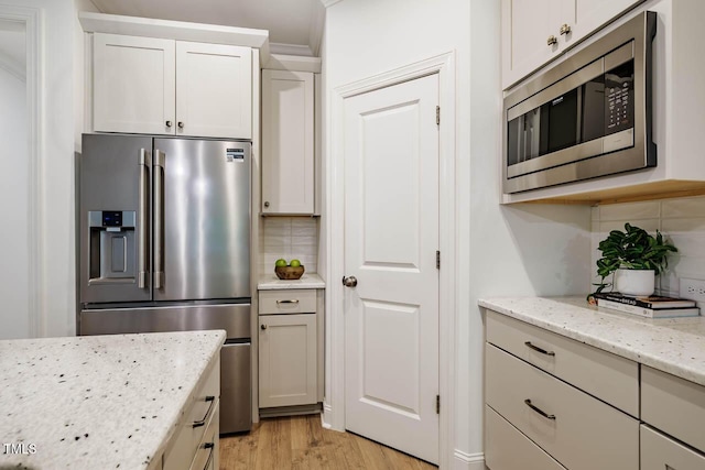 151 Monteith Dr, Chapel Hill, NC 27516 - kitchen featuring appliances with stainless steel finishes, tasteful backsplash, light wood-style flooring, light stone counters, and white cabinetry
