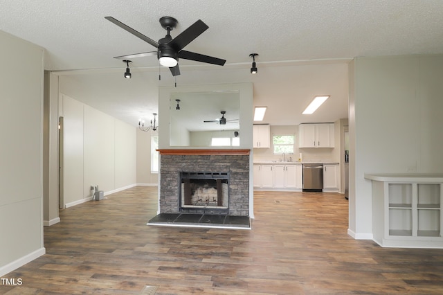 1201 Red Sunset Pl, Siler City, NC 27344 - unfurnished living room with wood finished floors, ceiling fan with notable chandelier, a fireplace, and a sink