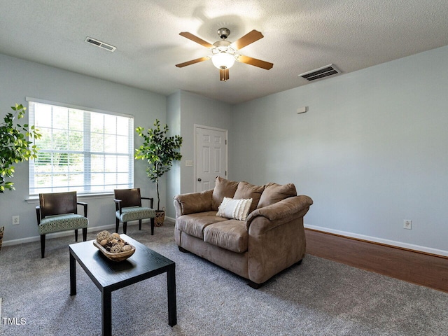 living room with a ceiling fan, carpet flooring, baseboards, and a textured ceiling