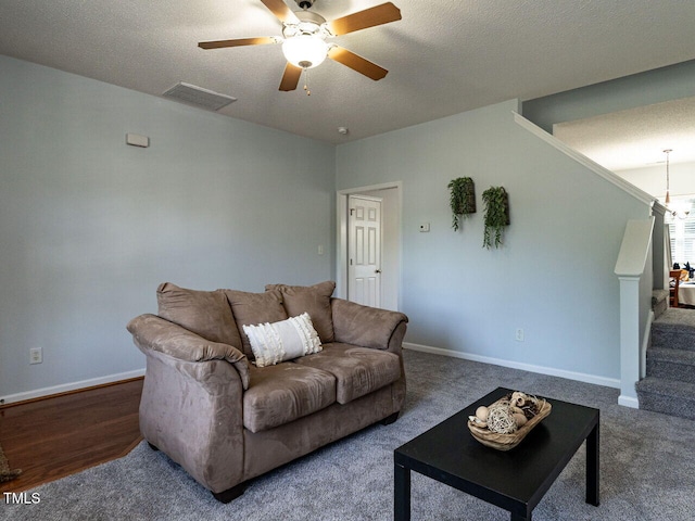 carpeted living room with ceiling fan, stairs, a textured ceiling, and baseboards