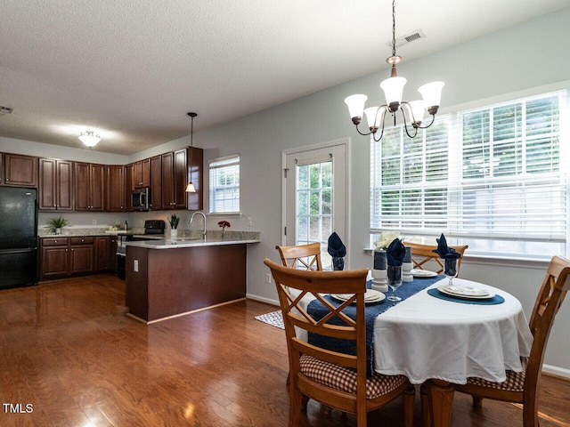 dining area featuring a chandelier, dark wood finished floors, a textured ceiling, and baseboards
