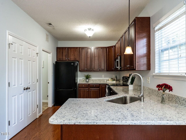 kitchen with black appliances, dark wood-style floors, a sink, light stone countertops, and a textured ceiling