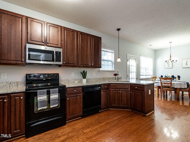 kitchen featuring black appliances, a sink, dark wood finished floors, a textured ceiling, and a peninsula