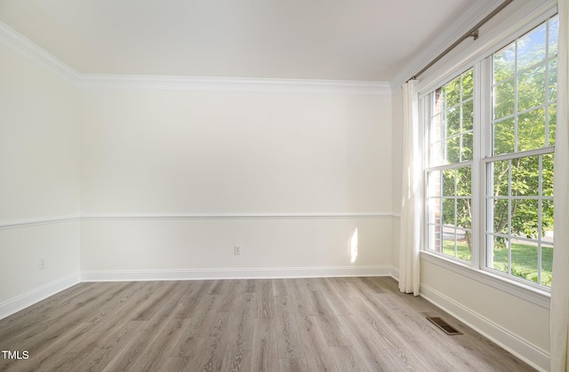 unfurnished room featuring crown molding, baseboards, visible vents, and light wood-type flooring