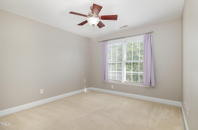spare room featuring baseboards, visible vents, and light carpet