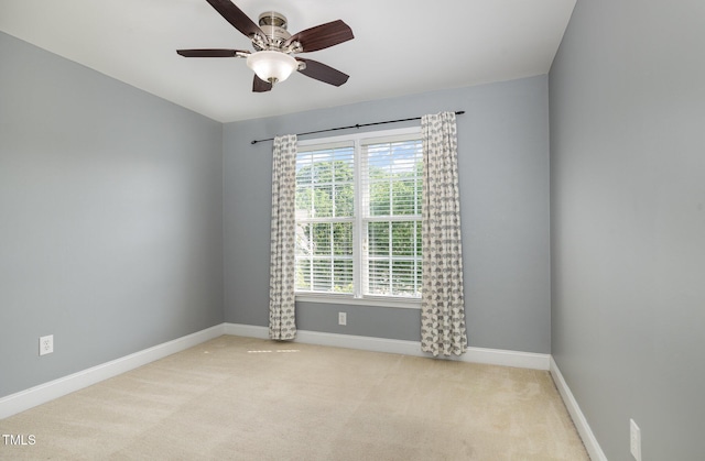 carpeted empty room featuring a ceiling fan and baseboards