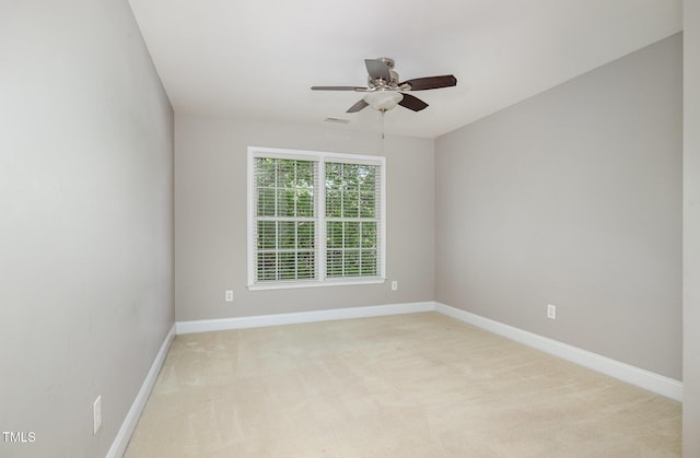 spare room featuring baseboards, a ceiling fan, and light carpet