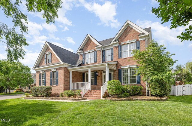 view of front of house featuring covered porch, brick siding, and a front lawn