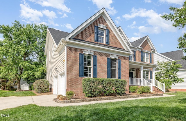 view of front of house with covered porch, a front yard, brick siding, an attached garage, and driveway