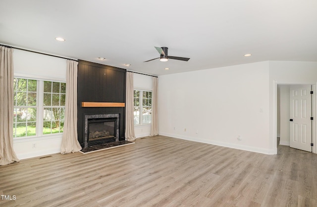 unfurnished living room with a ceiling fan, visible vents, light wood finished floors, and a fireplace
