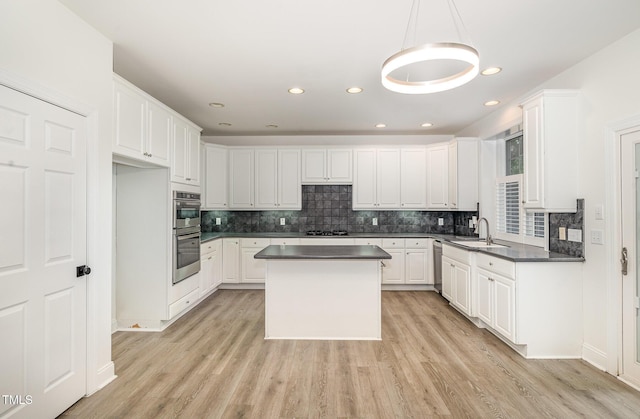 kitchen featuring a sink, dark countertops, white cabinets, and backsplash