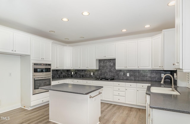 kitchen featuring light wood-type flooring, a sink, white cabinetry, and dark countertops