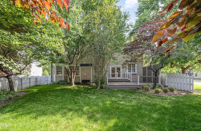 rear view of property featuring fence and a lawn