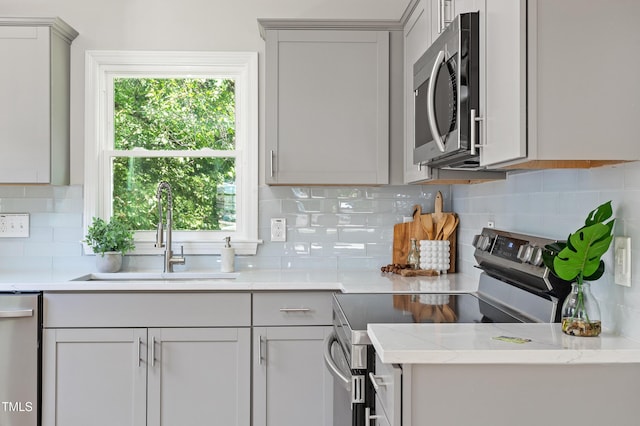 kitchen with stainless steel appliances, a sink, plenty of natural light, and tasteful backsplash