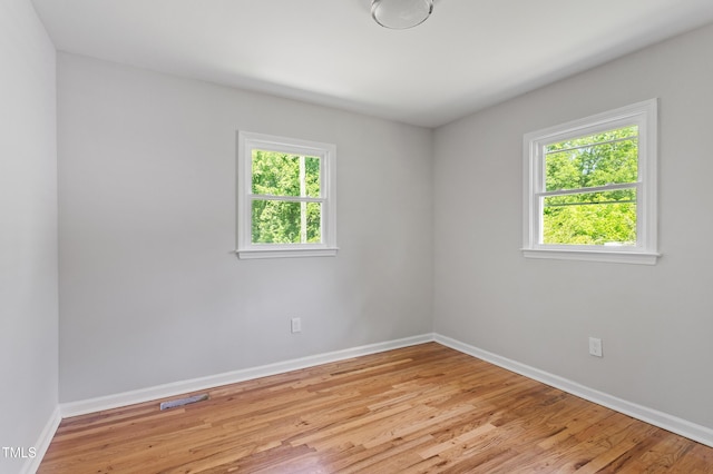unfurnished room featuring plenty of natural light, baseboards, and light wood-style flooring