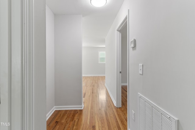corridor featuring light wood-type flooring and baseboards