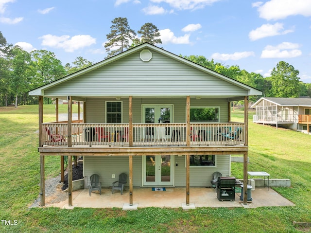 back of property with a lawn, french doors, a patio area, and a wooden deck
