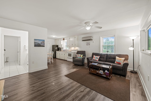 living area featuring an AC wall unit, baseboards, dark wood finished floors, and ceiling fan