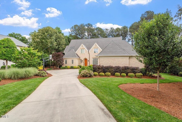 view of front of home featuring a front lawn, concrete driveway, and brick siding