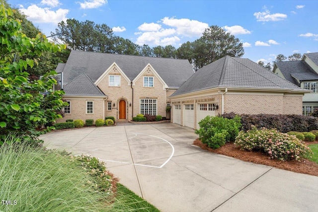 view of front of home with driveway, an attached garage, and brick siding