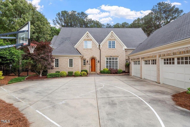 view of front of home with concrete driveway, brick siding, and basketball court