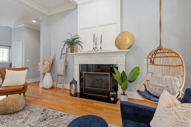 living room with crown molding, wood finished floors, a fireplace with flush hearth, baseboards, and recessed lighting