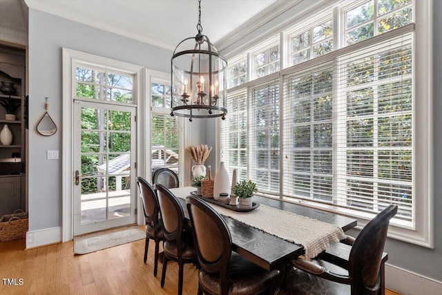 dining area with a chandelier, light wood finished floors, ornamental molding, and baseboards