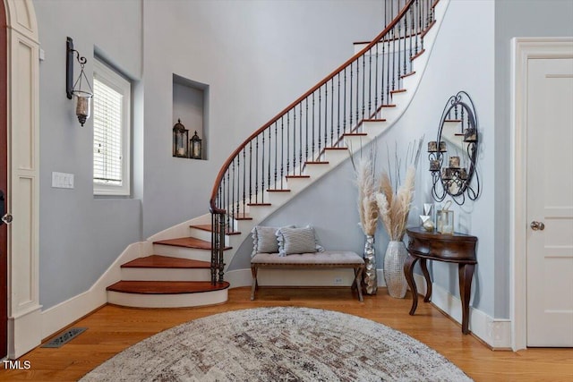 foyer with stairs, wood finished floors, and baseboards