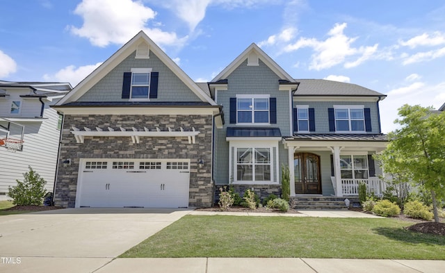craftsman-style home with covered porch, stone siding, a front yard, an attached garage, and driveway