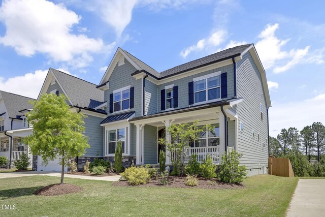 view of front of house with a porch, roof with shingles, fence, and a front yard