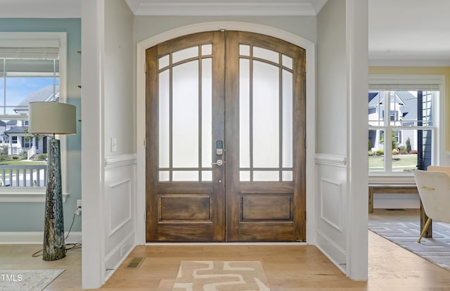 entryway featuring french doors, light wood-style floors, crown molding, and visible vents
