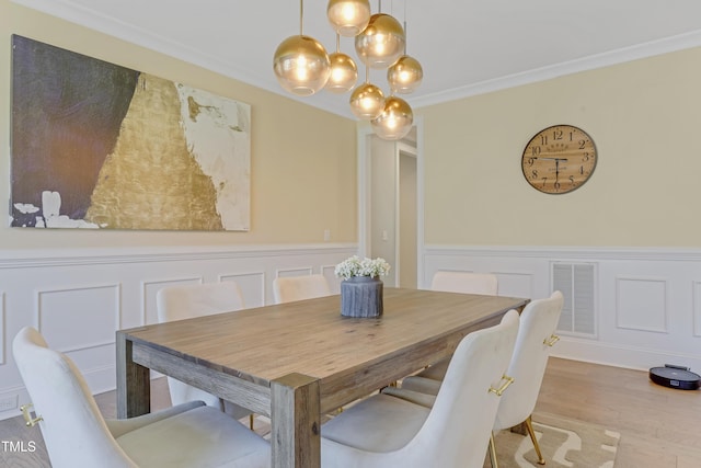 dining area with visible vents, a decorative wall, a wainscoted wall, and an inviting chandelier