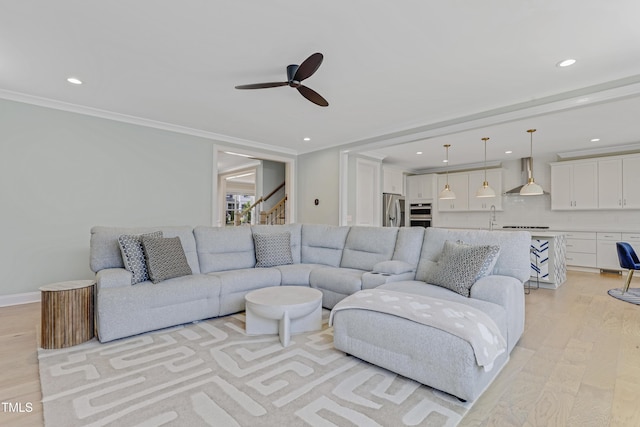 living room featuring crown molding, ceiling fan, stairway, light wood-type flooring, and recessed lighting