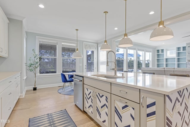 kitchen featuring a kitchen island with sink, dishwasher, a sink, light countertops, and open floor plan