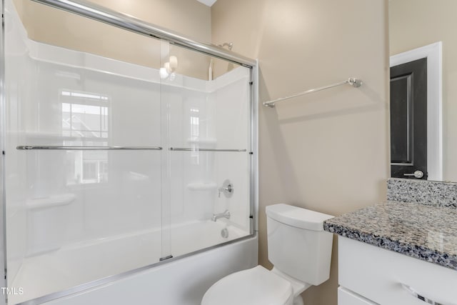 bathroom featuring vanity, combined bath / shower with glass door, and toilet
