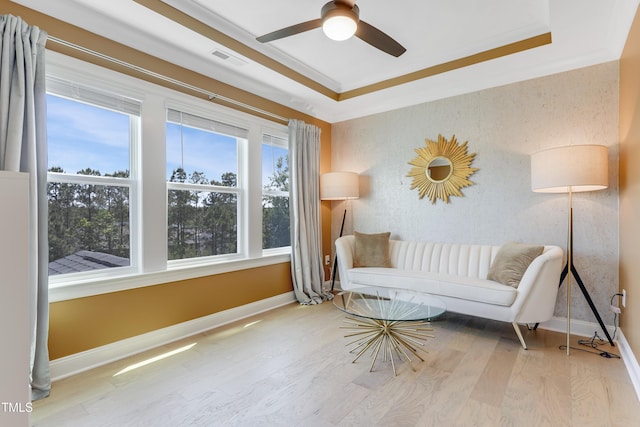 living area featuring visible vents, a raised ceiling, baseboards, and wood finished floors